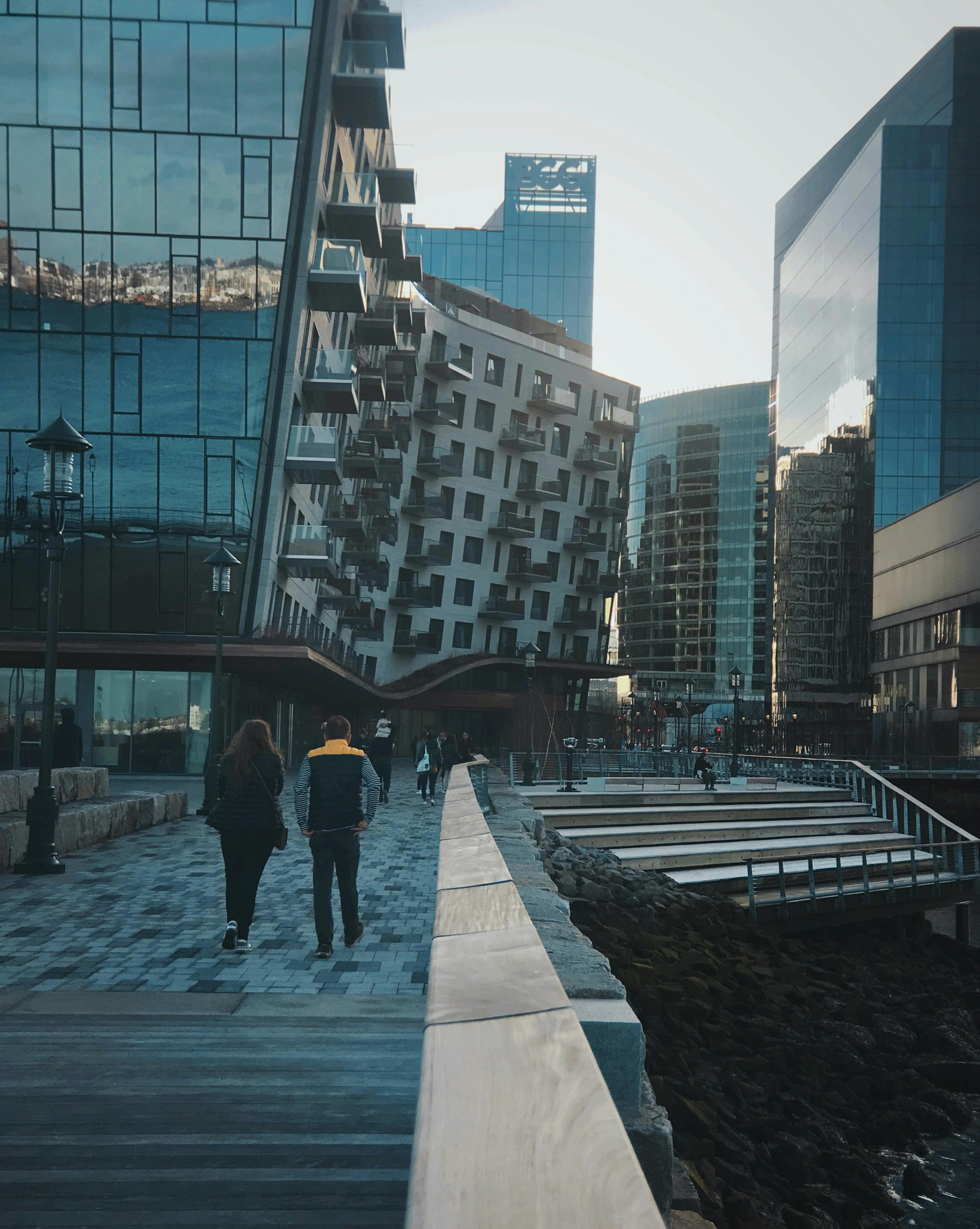 People walking along the Boston Seaport waterfront with modern buildings