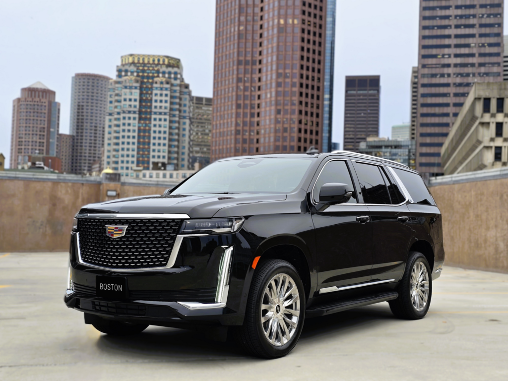 Black Cadillac Escalade parked on a rooftop with Boston city skyline in the background