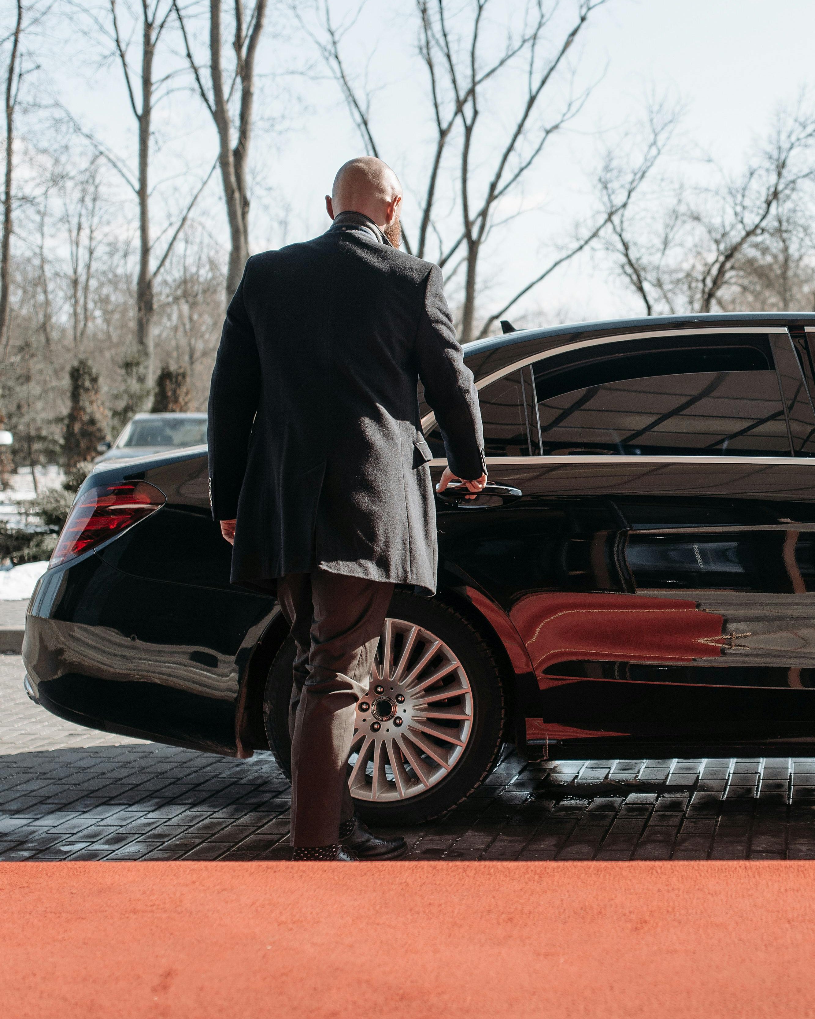 Chauffeur opening door for a guest arriving in a black mercedes
