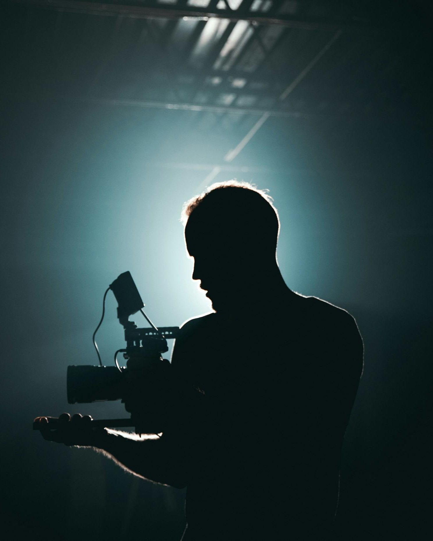 Silhouette of a videographer holding a camera in low light
