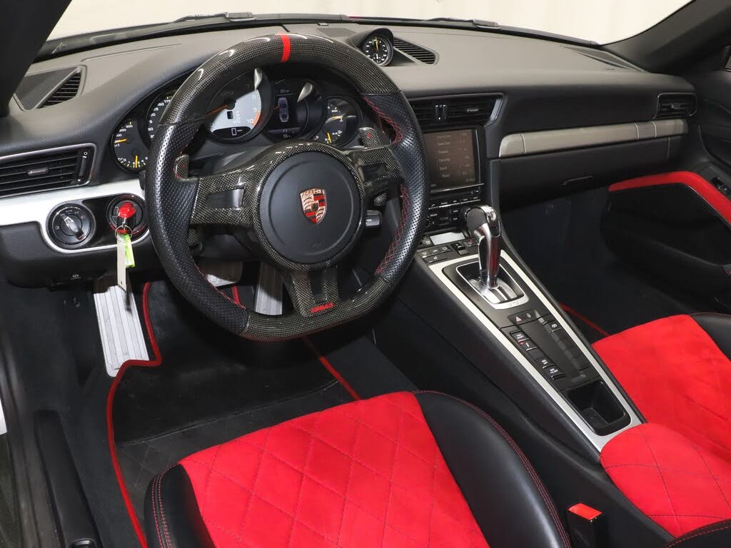 Interior of a Porsche 911 GT3 featuring red and black sport seats, steering wheel, and dashboard
