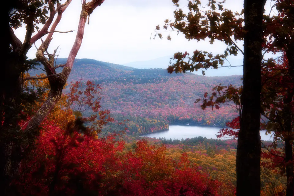 Red and orange fall foliage framing a lake and mountains in New England