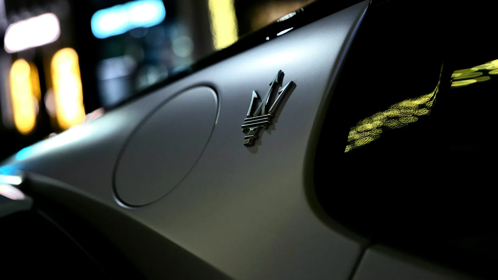 Maserati trident badge on the hood at night, representing the Ghibli Q4 available to rent in Boston
